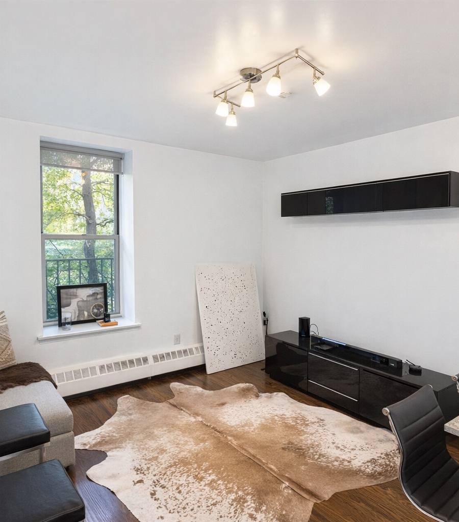 Bright modern living room with a cowhide rug, black media console and daylight through a large window after real estate photo enhancement