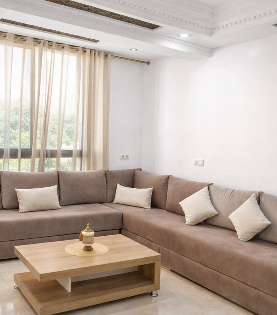 Bright traditional Moroccan-style living room with a taupe sectional, sheer curtains and ornate ceiling molding after photo enhancement